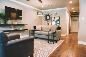 Relax in this stylish living room with a flat-screen TV, comfortable sofa, and cozy armchair.