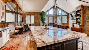 A spacious kitchen with a large island, stone walls, and large windows.