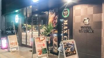 A hotel entrance with a sign for 'Max Cafe' and 'Max Hotel Livemax'.