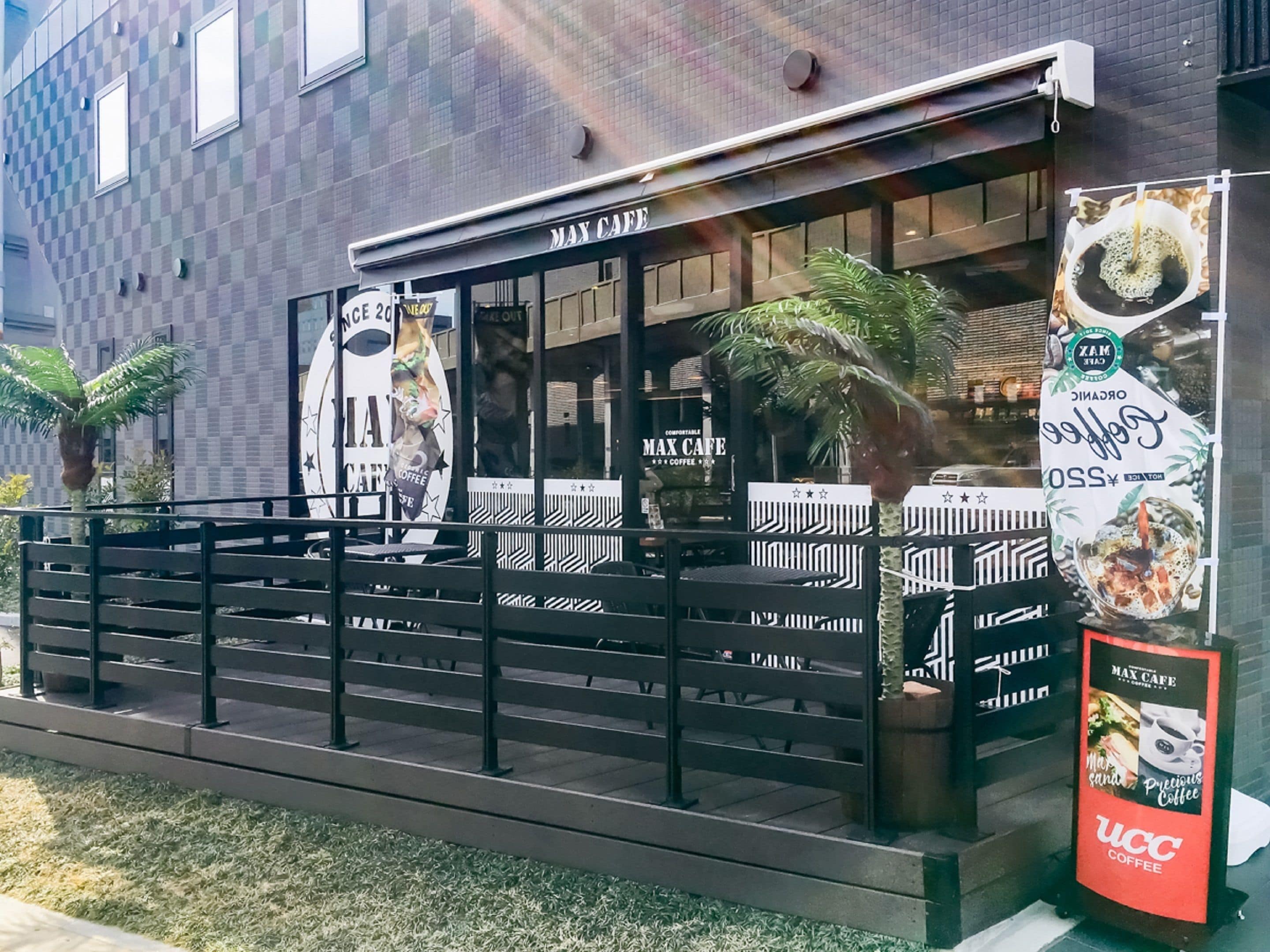 A cafe with outdoor seating, a signboard, and a building in the background.