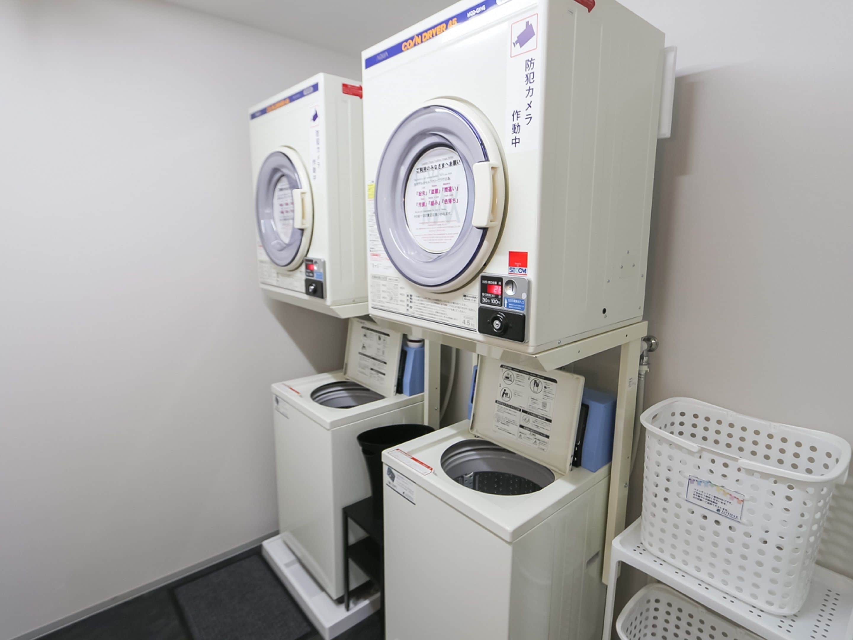 A laundry facility with multiple washing machines and a basket rack.