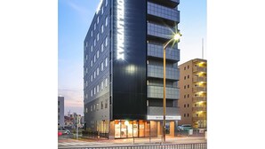 Een modern hotelgebouw met een opvallend 'HOTEL MAX' bord, meerdere verdiepingen en een goed verlichte entree.