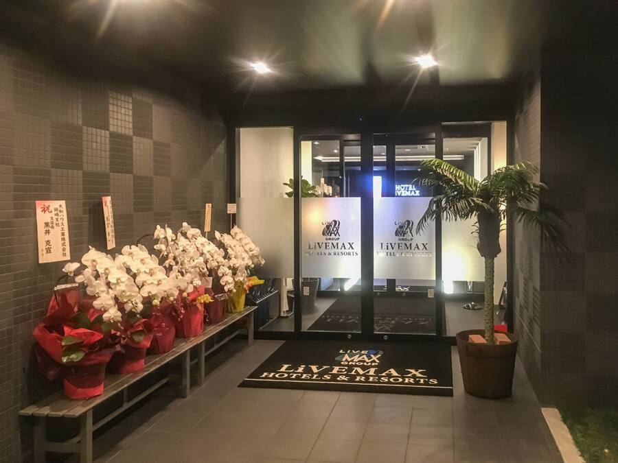 Ein Hotel Eingangsbereich mit einer Rezeption, einer Bank mit Blumenarrangements und einer Topfpflanze.