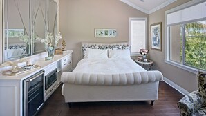 A bedroom with a large bed, a dresser, a vanity, and a window with a view of greenery. - Stunning golf course view vacation home (Tustin)