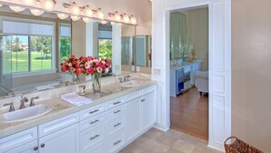 A spacious bathroom with two sinks, a large mirror, and a vase of flowers. - Stunning golf course view vacation home (Tustin)