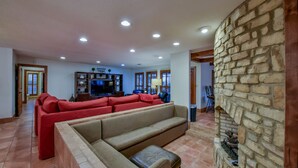 Una sala de estar con chimenea de piedra, un sofá rojo grande y un televisor.