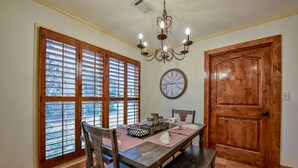 Un comedor con mesa de madera, sillas, candelabro y un reloj en la pared.