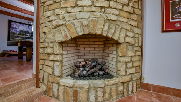 Una chimenea de piedra con un arco de ladrillo, un banco de madera y un cuadro en la pared.