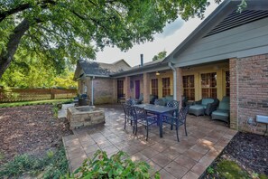 A patio with outdoor furniture, a stone fire pit, and a brick building with a covered porch. - Myrtlewood Cottage- Book for Football Season! Walk to the Stadium! (Tuscaloosa)