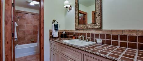 A bathroom with a bathtub, a sink, and a mirror.