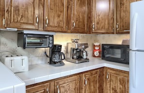 Eine Küche mit Holzausstattung, einem Toaster, einer Kaffeemaschine, einer Mikrowelle und einem Kühlschrank.