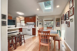A kitchen with wooden cabinets, a dining table, and chairs. There is a skylight above the kitchen. - (42R) Rosenberg's Creekside Cabin at The Redwoods In Yosemite (Yosemite National Park)