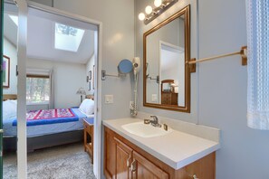A bedroom with a bed, a bedside table, a lamp, and a window. - (42R) Rosenberg's Creekside Cabin at The Redwoods In Yosemite (Yosemite National Park)
