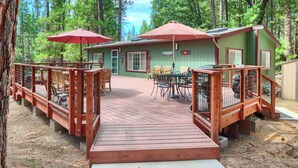 Une terrasse en bois menant à un bâtiment doté d’un espace extérieur aménagé et d’une zone couverte.