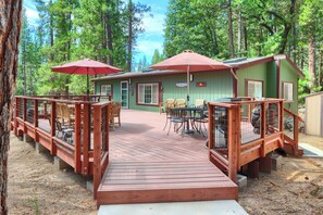 A wooden deck leading to a building with outdoor seating and a covered area. - (42R) Rosenberg's Creekside Cabin at The Redwoods In Yosemite (Yosemite National Park)