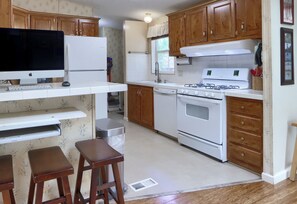 Una cucina con mobili in legno, un frigorifero bianco, un fornello e una lavastoviglie.