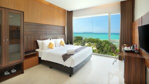 Een moderne hotelkamer met een groot bed, een televisie en uitzicht op de oceaan.