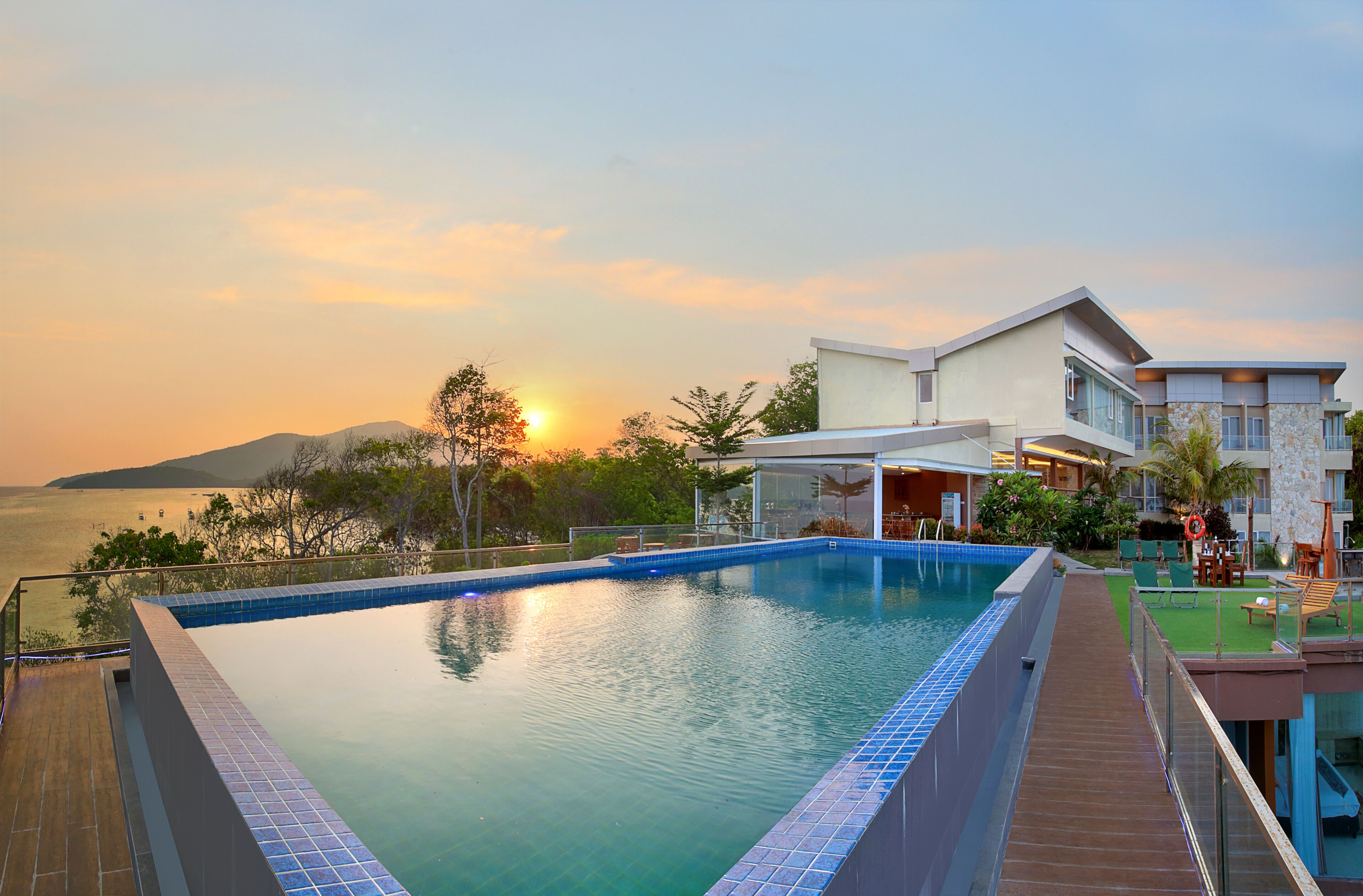 A swimming pool with a view of the sunset and a mountain in the background.