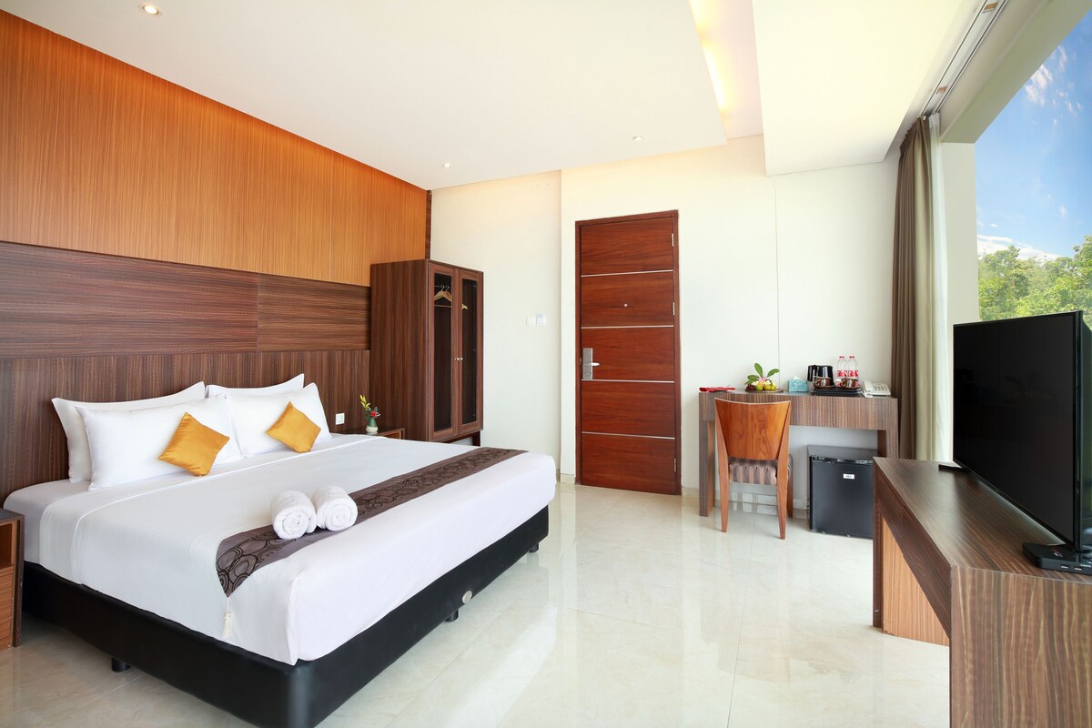 Een moderne hotelkamer met een groot bed, een bureau, een televisie en een kledingkast.