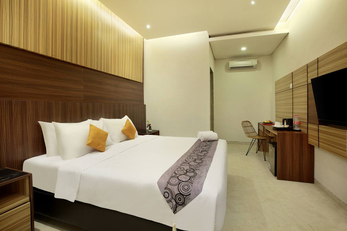 A modern hotel room with a large bed, a desk, and a TV.