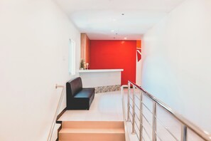 A modern interior with a staircase, a red accent wall, and a black bench. - Trip Inn Near Airport or City Center (Legazpi)