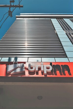 A building with a modern architectural design, featuring a prominent 'tripinn' sign at the ground level. - Trip Inn Near Airport or City Center (Legazpi)