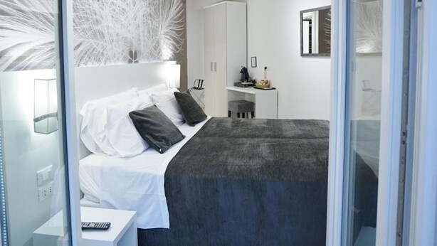 A modern bedroom with a large bed, a bedside table, and a desk area. - Duca's House (Rome)