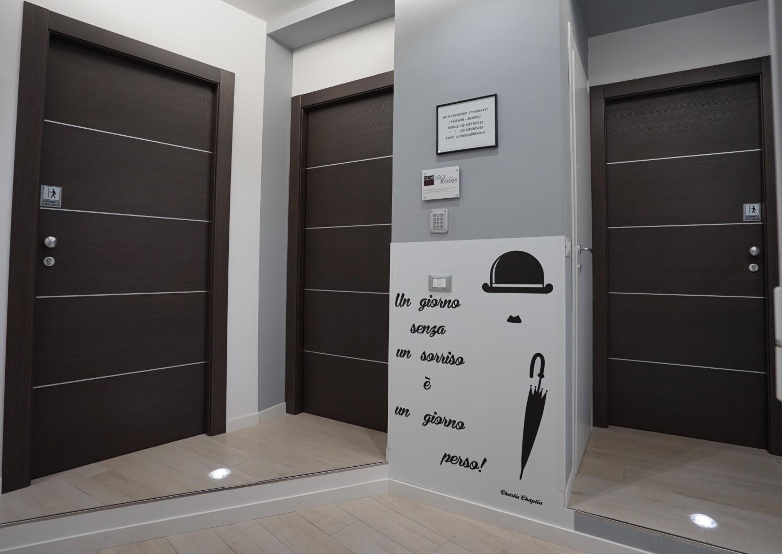 Interno di un ascensore moderno con porte in legno scuro, una parete bianca con una citazione motivazionale e una piccola targa.