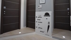A modern elevator interior with dark wooden doors, a white wall with a motivational quote, and a small plaque. - Duca's House (Rome)