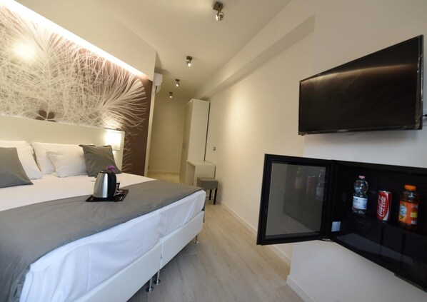 A modern hotel room with a bed, bedside table, TV, and a minibar. - Duca's House (Rome)