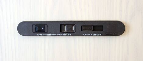 A black device with three ports on a light wooden surface.