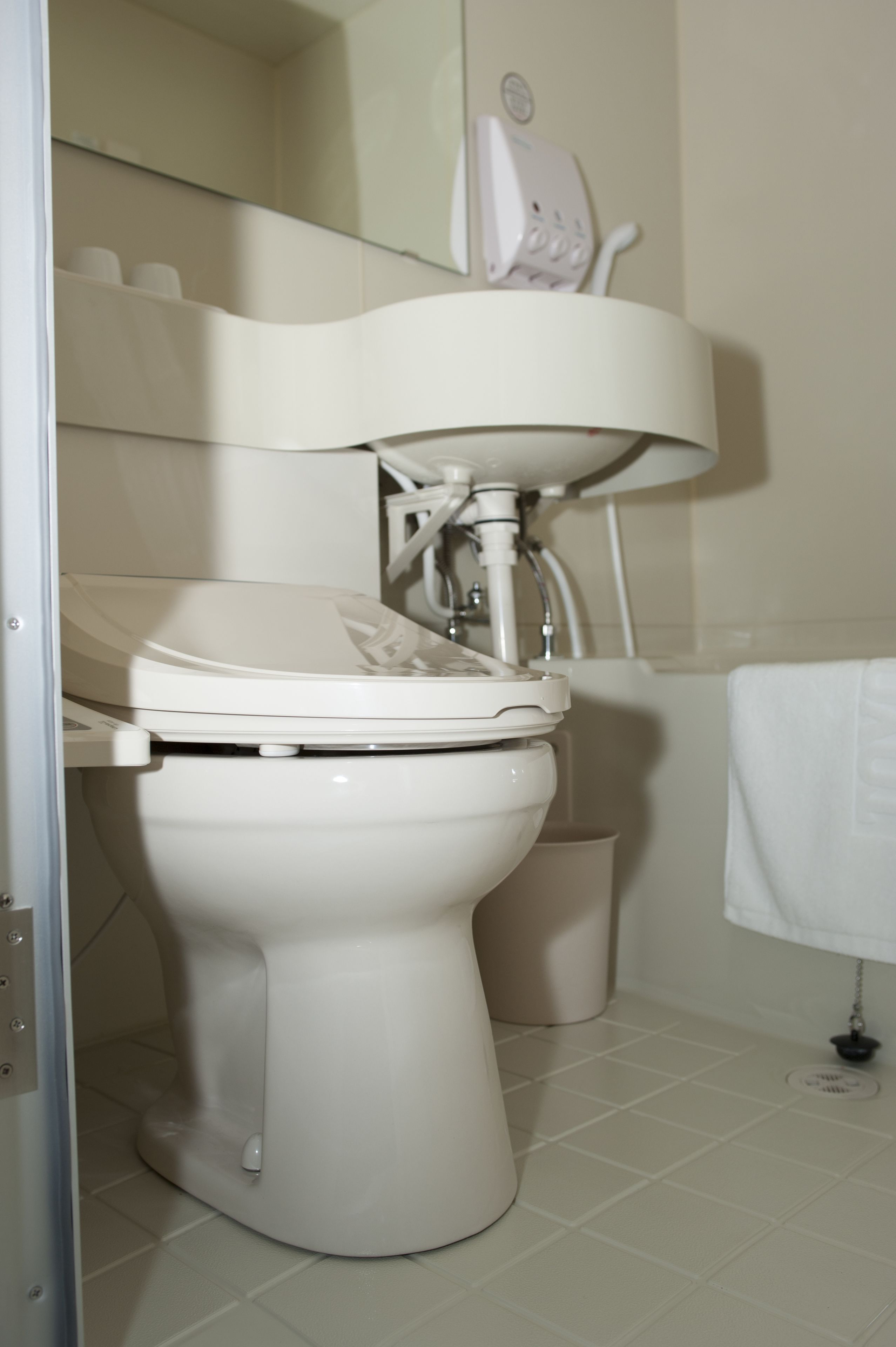 A bathroom with a toilet, sink, and a mirror.