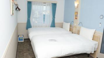A hotel room with a large bed, a bedside table, a window with curtains, a wall clock, and a small bedside table with a lamp.