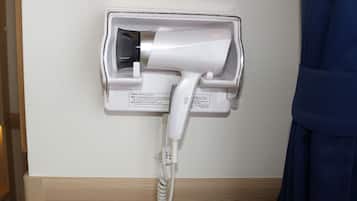 A hair dryer mounted on a wall with a cord.