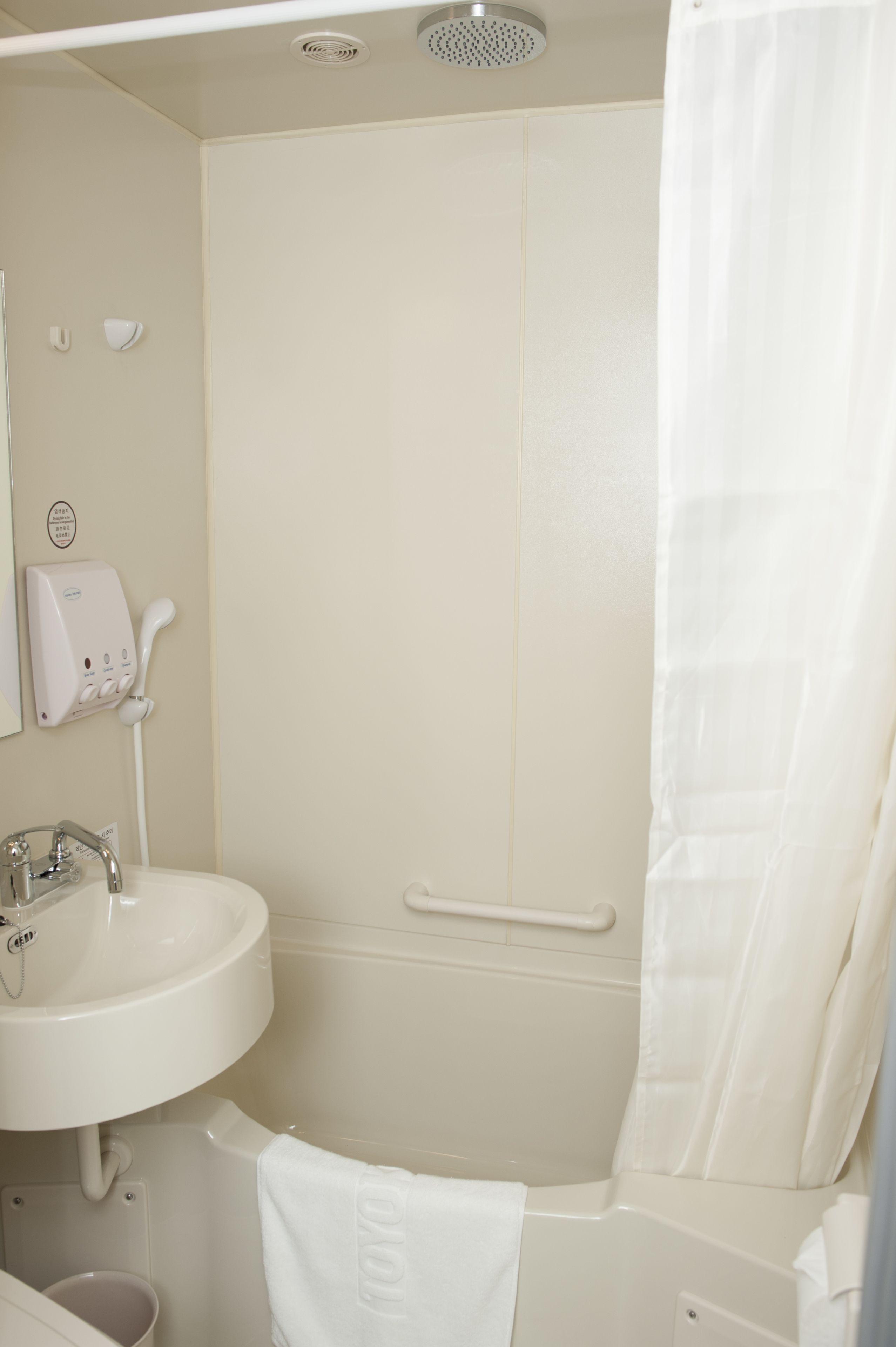 Een badkamer met een wastafel, een handdouche, een handdoekhouder en een douchegordijn.