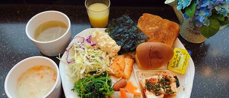 A meal tray with soup, salad, tofu, and bread, along with a glass of orange juice.