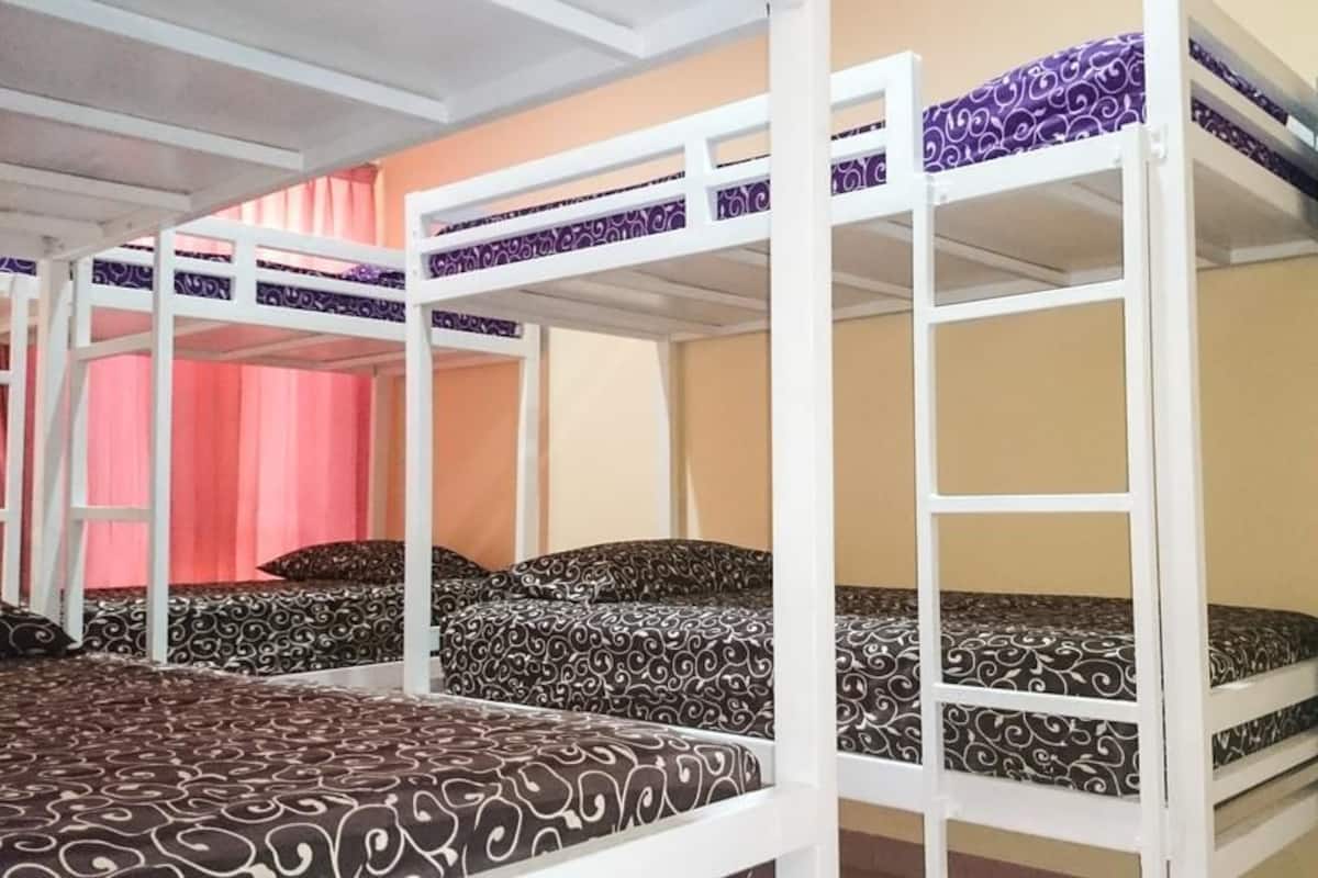 A bunk bed room with patterned bedding, a wardrobe, and a pink curtain.