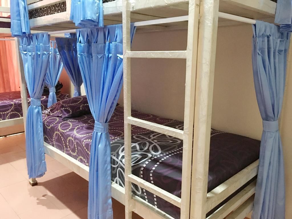 A bunk bed with blue curtains, patterned bedding, and a wooden frame.