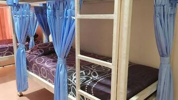 A bunk bed with blue curtains, patterned bedding, and a wooden frame.