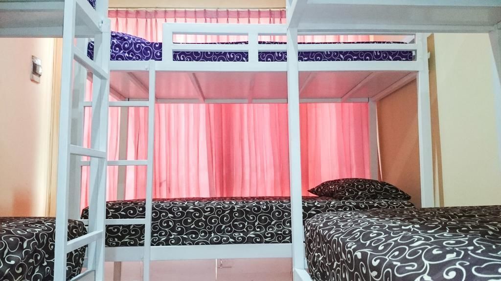 A bunk bed room with pink curtains and patterned bedding.