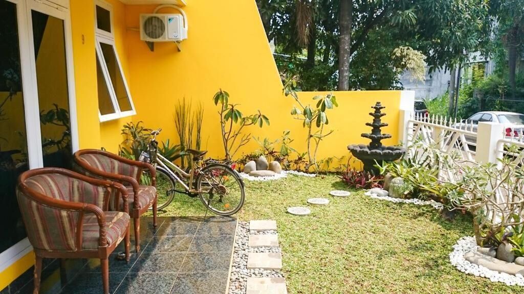 A yellow building with a tiled patio, a bicycle, and a fountain.