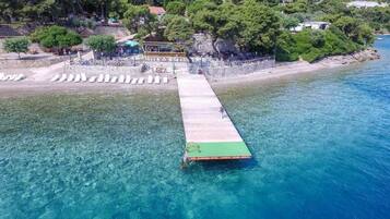 A pier extending into clear blue water with a small boat docked at the end.