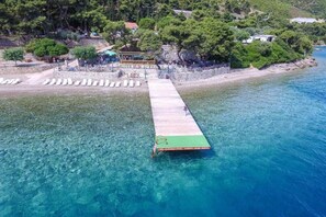 A pier extending into clear blue water with a small boat docked at the end. - Tsolis Village (Aigialeia)
