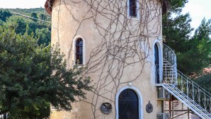 A cylindrical tower with arched windows and a spiral staircase. - Tsolis Village (Aigialeia)