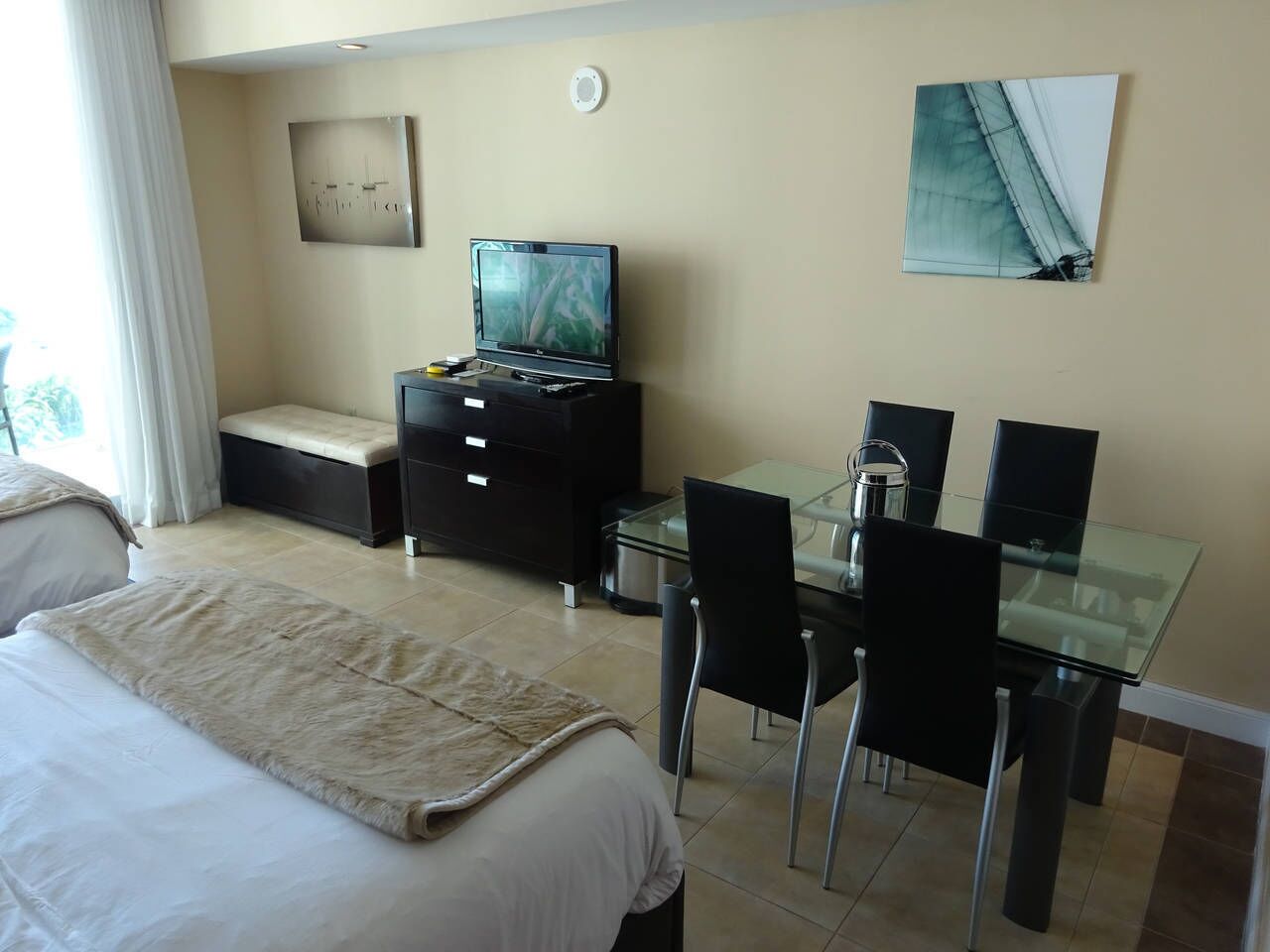 Ein Hotelzimmer mit einem Bett, einem Schreibtisch mit Fernseher, einem Glastisch und Stühlen.