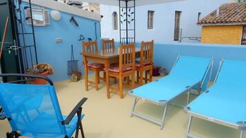 Una stanza con una parete blu, un tavolo da pranzo in legno con sedie, un tavolo pieghevole blu e una sedia pieghevole blu.