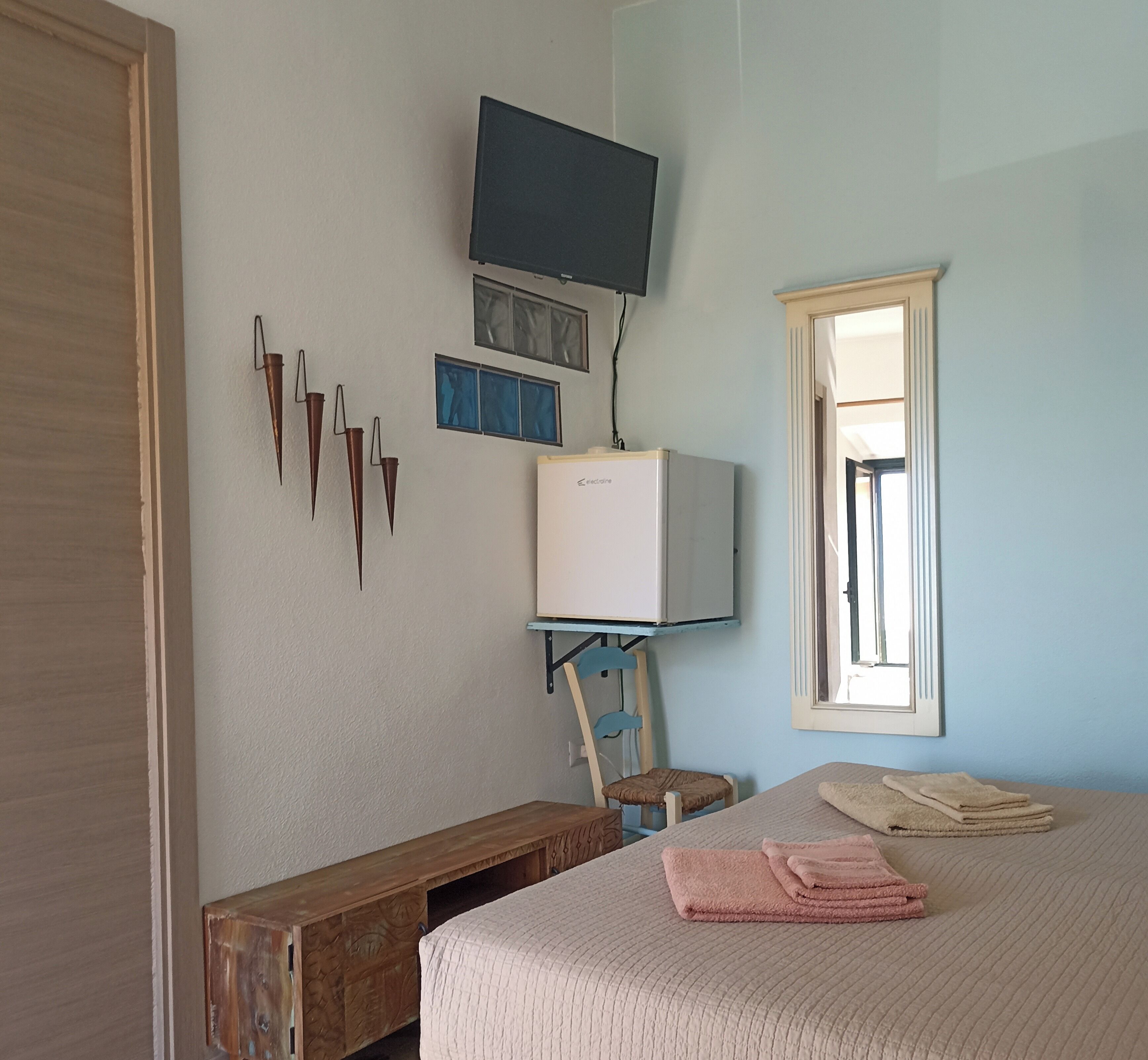 Een slaapkamer met een bed, een aan de muur bevestigde televisie, een raam en een radiator.