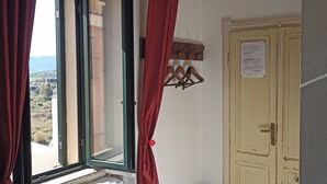 A room with a window, a door, and a small trash bin. - B&B Eleonora D'Arborea (Posada)