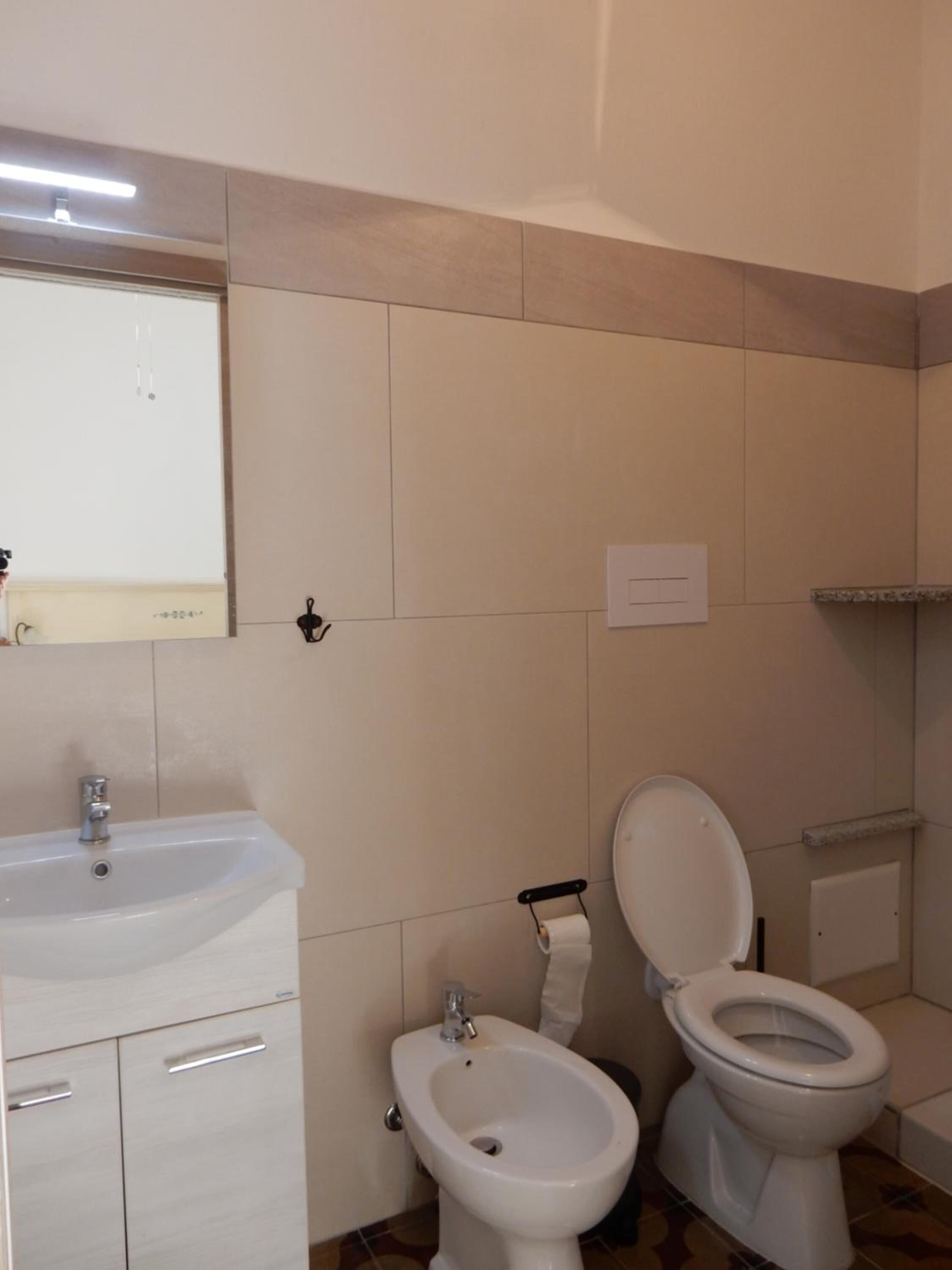 A bathroom with a sink, bidet, toilet, and a mirror.
