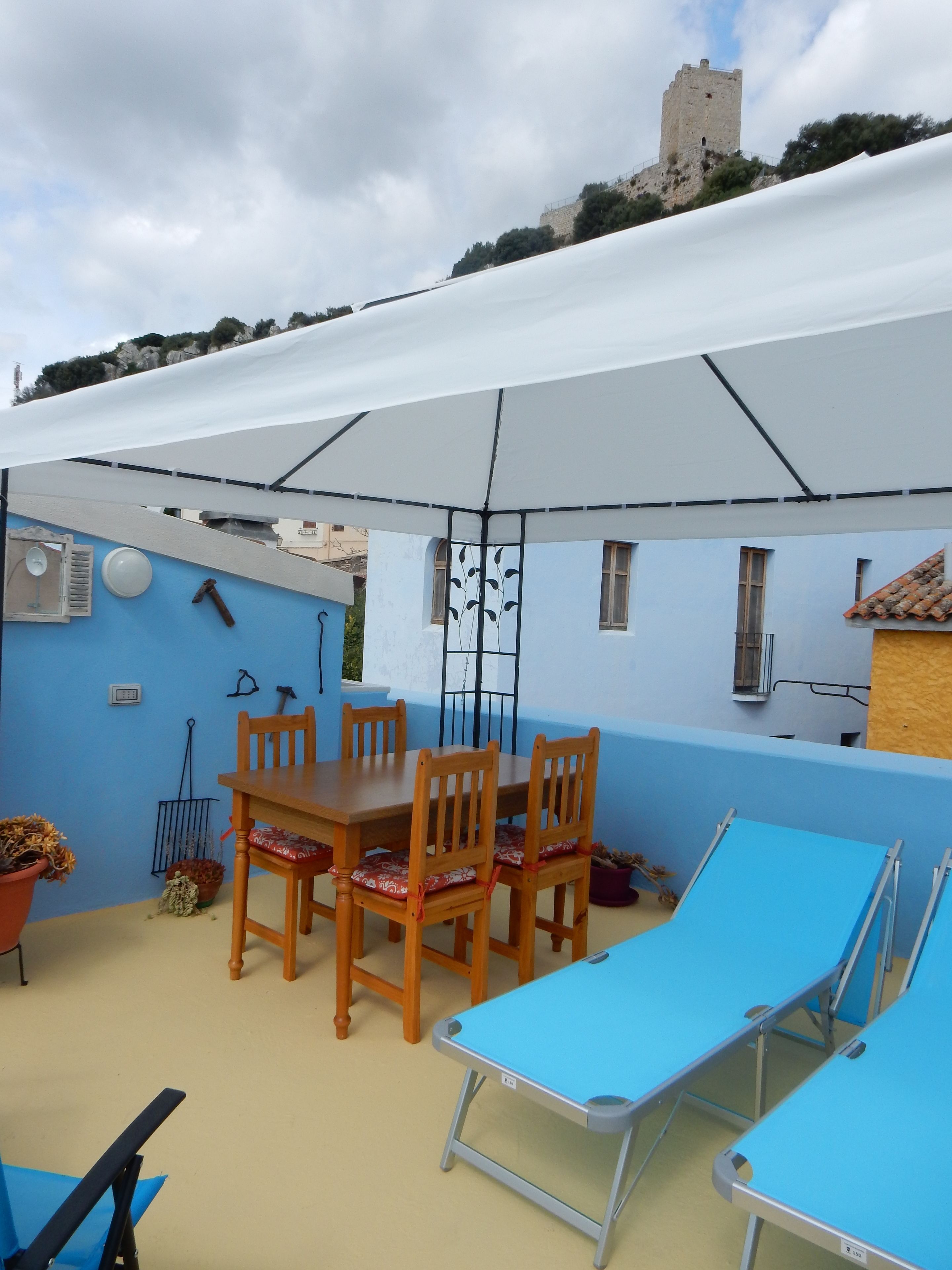 Un patio con una mesa y sillas, una tumbona y vistas a un castillo.